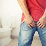Person sitting on a toilet, highlighting risks of prolonged sitting causing hemorrhoids.
