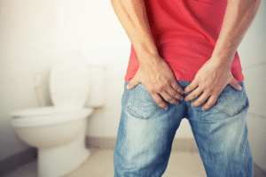 Person sitting on a toilet, highlighting risks of prolonged sitting causing hemorrhoids.